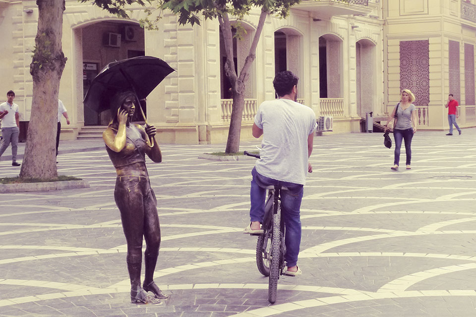 Bronze statue in Baku’s Fountain Square of a young woman in contemporary attire talking on a mobile phone, erected in 2014.