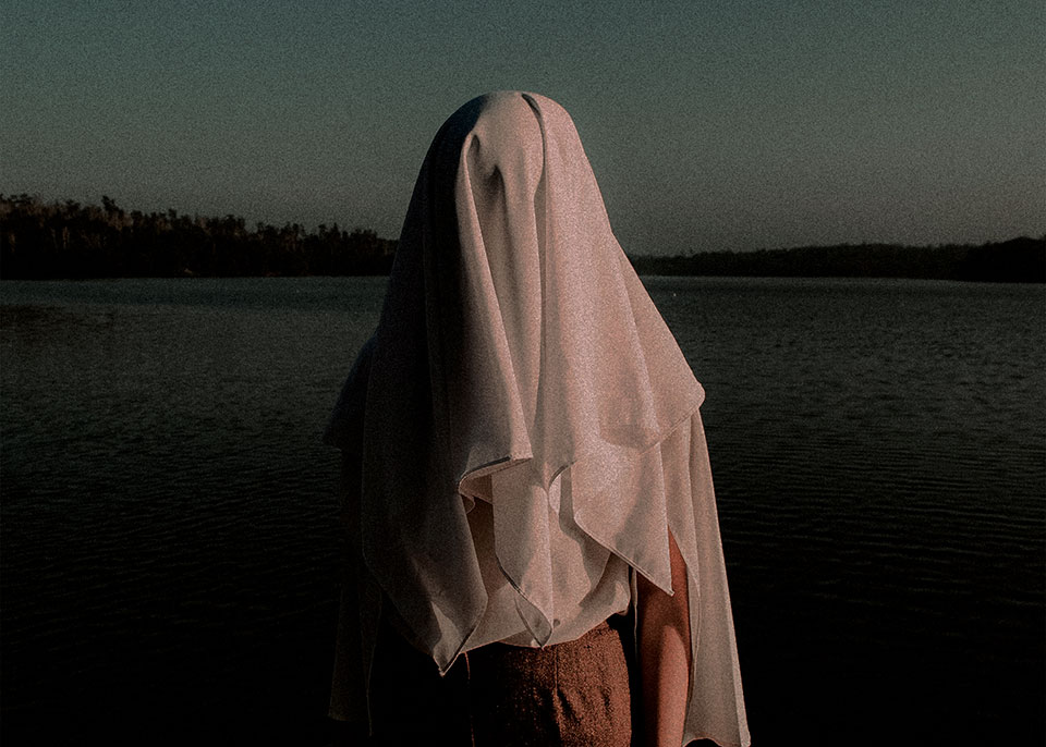 A photograph of a human figure draped in loose, white cloth