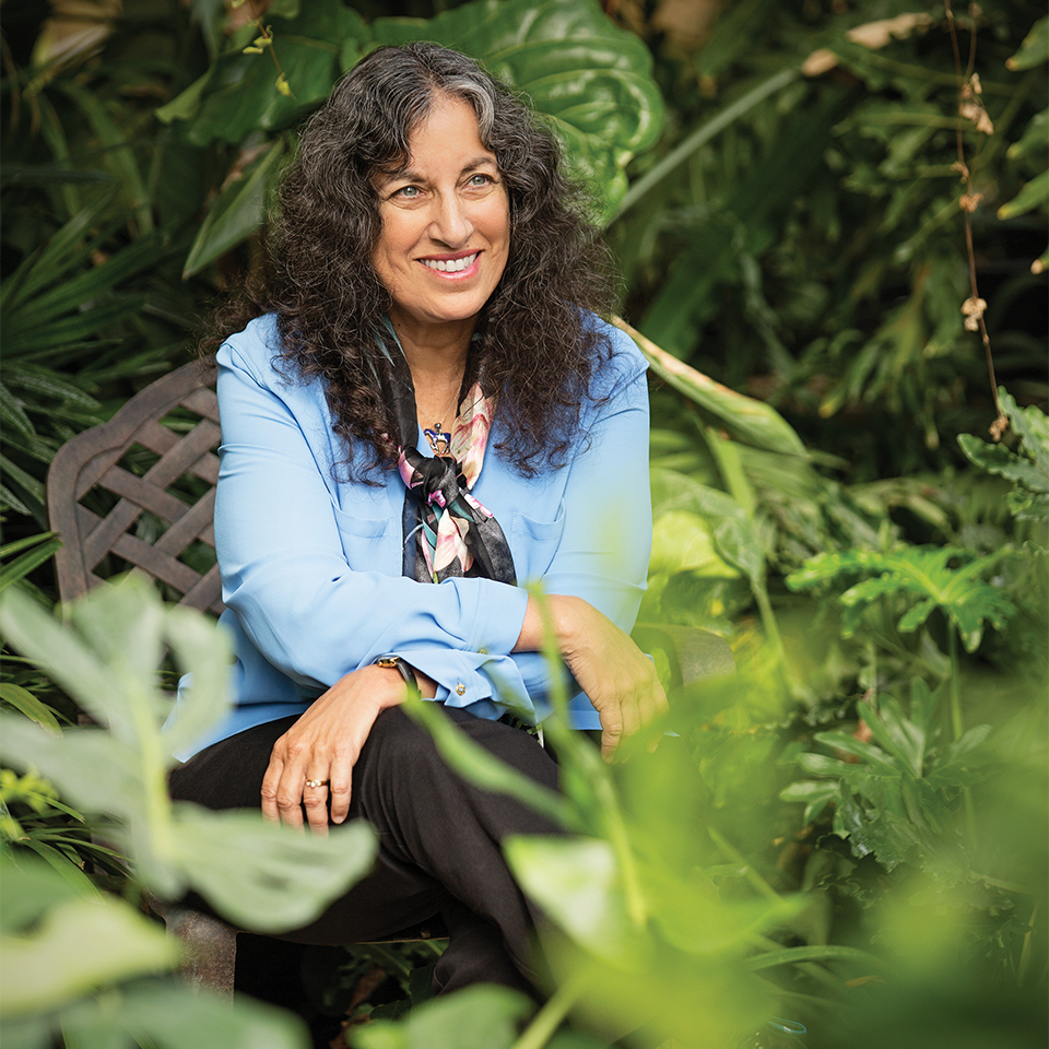 Margraita Engle sits crosslegged surrounded by plants