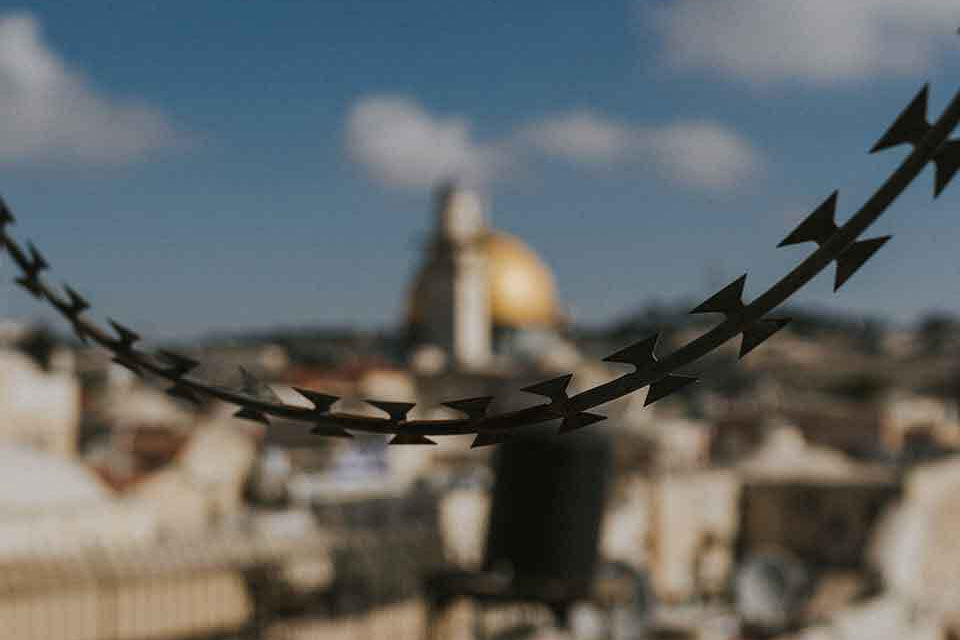 Jerusalem hangs out of focus in the background as a chain hangs across the image in the foreground