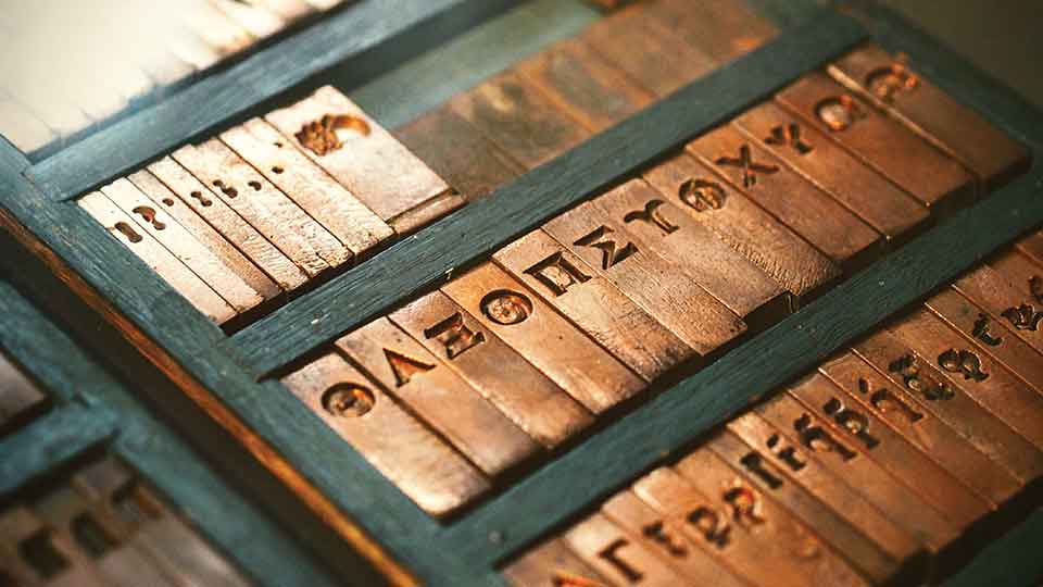 A photograph of Greek letters inscribed in typographical brass fonts