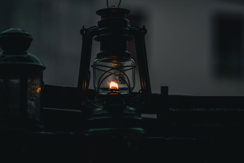 A photograph of a low light from inside of a lantern at dusk