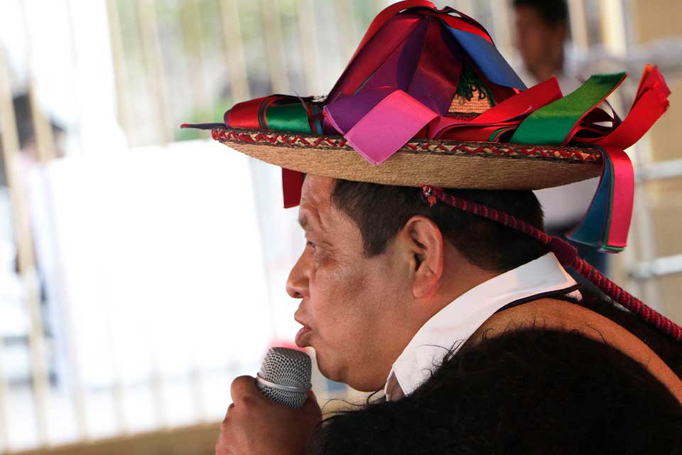 A photograph of a man in a colorful talking into a microphone