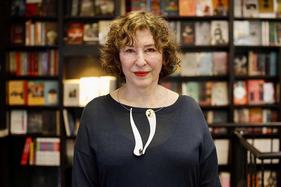 A photograph of Azar Nafisi posing in front of a book shelf