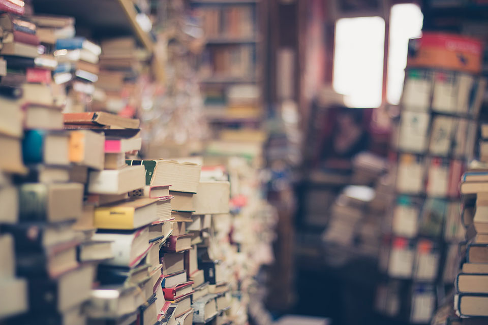 Stacks of books in a room with a window