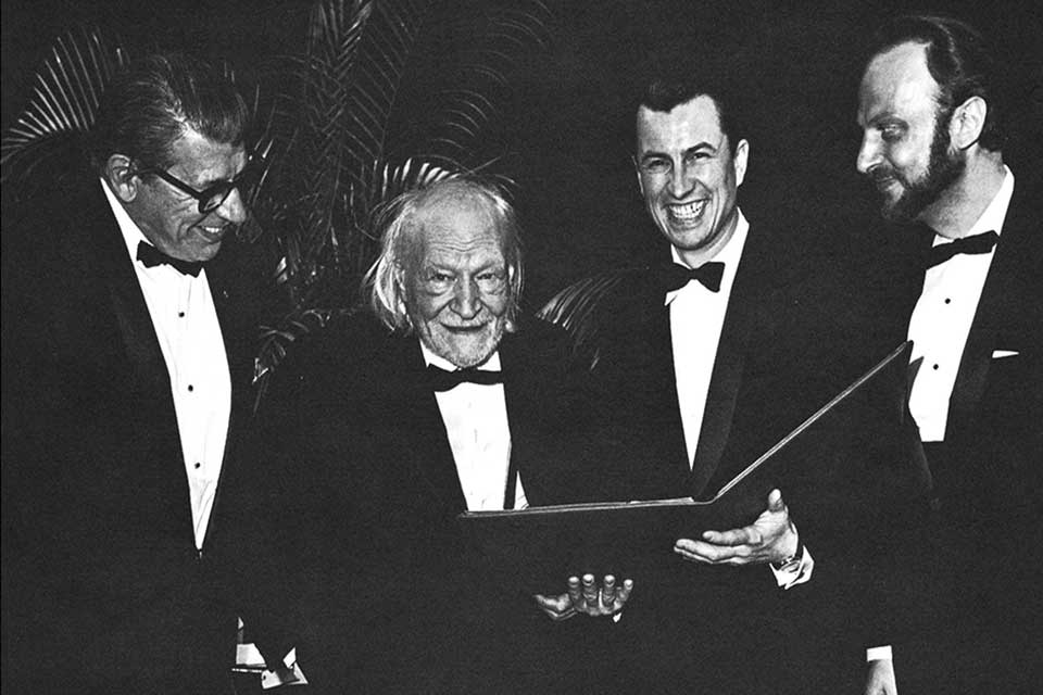 A black and white photo of four men standing in tuxedos