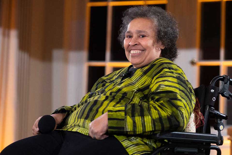 A photograph of Katharina Oguntoye smiling in a wheelchair