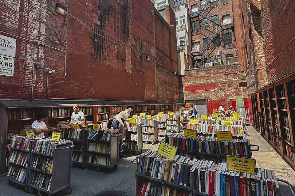 Racks of books on sale outdoors in a city alleyway