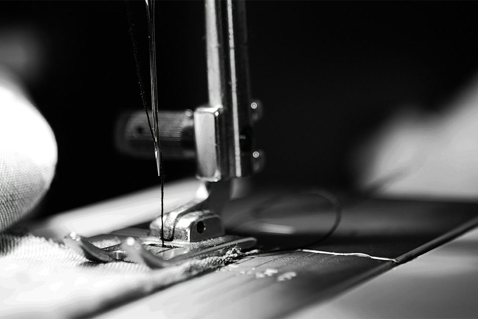 A black and white photograph showing a close up of a sewing machine at work