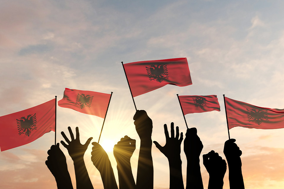 A photograph of hands waving small flags at sunset