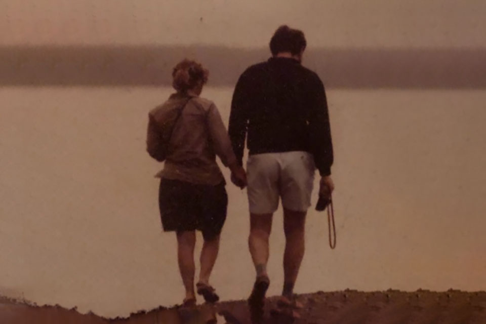 An aged photograph of a couple walking along a beach