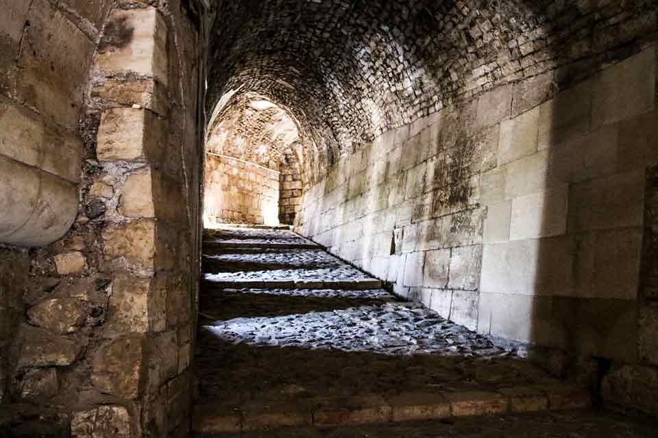 A photograph taken from inside a covered stone hallway