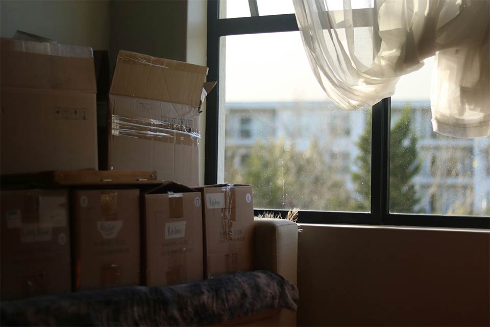 A photograph of a stack of boxes dimly lit by a window nearby