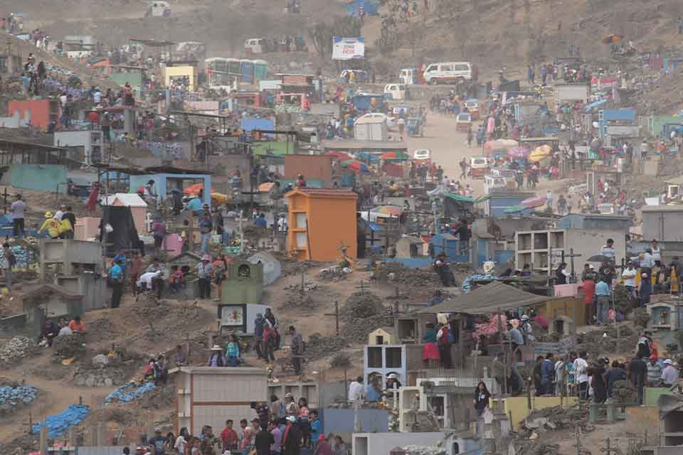 An aerial shot of a chaotic scene of hundreds of families holding simultaneously holding funerals in a massive open area