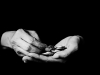 A black and white photograph of a hand holding coins