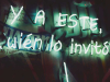 A neon sign glows in the shadows of night. The text reads 'Y A Este wién lo invito"