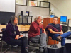 Three people sitting in chairs in conversation with an audience (which is off panel)