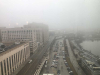 An aerial photograph of a crowded parking lot on a waterfront, shrouded in fog