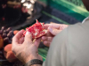 A photograph taken over a man's shoulder as he opens a pomegranate.