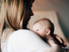 A photograph of a woman holding a baby. Her face is in shadow