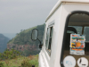 A photograph taken from directly behind a white vehicle as it travels on a wilderness landscape