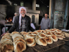 A photograph of two men, smiling at the camera, standing behind a table full of freshly baked bread