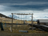 A desolate playground sits in the foreground on dried grass with a glacier in the background