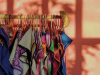 A photograph of a rack of brightly colored clothing on hangers