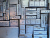 Many pieces of luggage, all spray painted uniformly with a metallic sheen, stacked into a wall