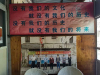 A photograph of several people standing in a row is mounted on a wall, beneath a banner adorned with Chinese characters