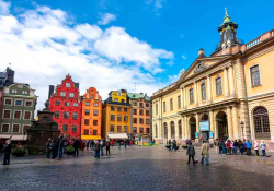 A photograph of a crisp Swedish buildings towering over a stone roadway