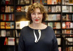 A photograph of Azar Nafisi posing in front of a book shelf